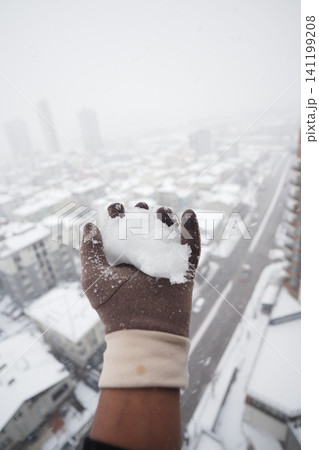 Snowball held high over a snowy city landscape 141199208