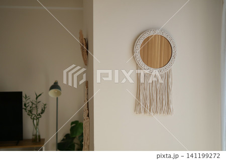 Decorative mirror with hanging fringe on wall in room Decorative mirror with hanging fringe on wall in room 141199272