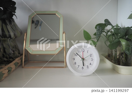 Clock and mirror on a shelf in a room Clock and mirror on a shelf in a room 141199297