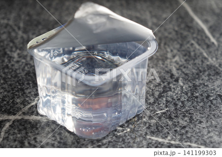 Clear plastic container filled with liquid on a surface Clear plastic container filled with liquid on a surface 141199303