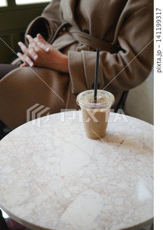 Sitting at a coffee shop with an iced drink on the table Sitting at a coffee shop with an iced drink on the table 141199317