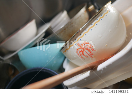 Dishes are stacked in a sink after a meal at home Dishes are stacked in a sink after a meal at home 141199321