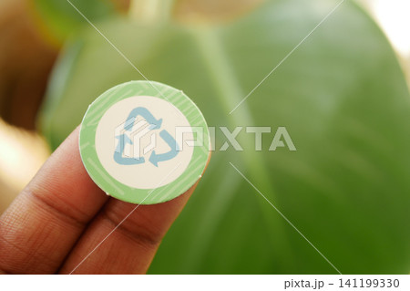 Recycling symbol sticker held by a person in nature 141199330