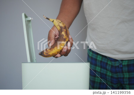 Disposing of a overripe banana in a trash bin 141199356
