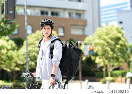 自転車で配達をする若いアジア人の男性配達員 141200210