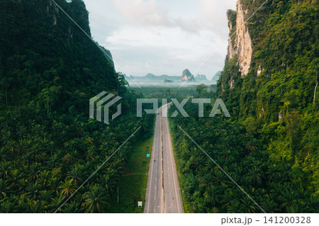 Aerial View of Scenic Green Road Cutting Through Limestone Mountains in Krabi 141200328