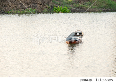 Small wooden boat floating calm river gentle reflections creating peaceful waterside landscape ideal for travel fishing nature outdoor backgrounds Small wooden boat floating calm river gentle reflections creating peaceful waterside landscape ideal for travel fishing nature outdoor backgrounds 141200569