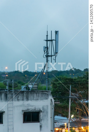 Cellular antenna installed rooftop above urban landscape supporting wireless communication mobile network connectivity modern telecommunications infrastructure at dusk Cellular antenna installed rooftop above urban landscape supporting wireless communication mobile network connectivity modern telecommunications infrastructure at dusk 141200570