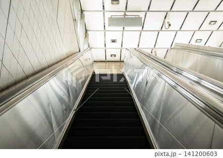 Modern escalator inside public transportation station clean architectural lines bright lighting stainless steel surfaces representing urban mobility infrastructure Modern escalator inside public transportation station clean architectural lines bright lighting stainless steel surfaces representing urban mobility infrastructure 141200603