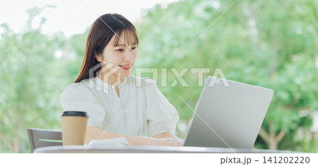 テラスでパソコンを使う若い女性 テラスでパソコンを使う若い女性 141202220