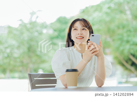 テラスでスマホを持つ若い女性 テラスでスマホを持つ若い女性 141202894
