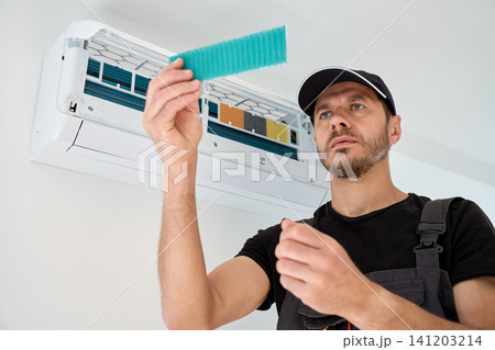 Man checking air conditioner filter during cleaning and maintenance 141203214