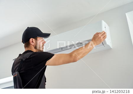 Air conditioner technician checking wall mounted AC unit during maintenance service Air conditioner technician checking wall mounted AC unit during maintenance service 141203218