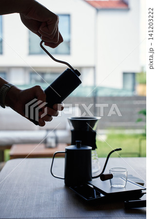Person grinding coffee with manual grinder by window Person grinding coffee with manual grinder by window 141203222