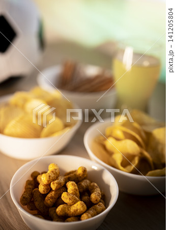 Assorted snacks and a beverage arranged on a tabletop, illustrating a game day snack table prepared for football fans. Assorted snacks and a beverage arranged on a tabletop, illustrating a game day snack table prepared for football fans. 141205804