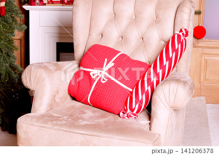 Cozy armchair with Christmas gifts and festive decorations in a warm room Cozy armchair with Christmas gifts and festive decorations in a warm room 141206378