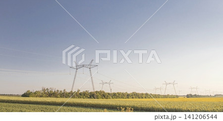 High voltage power lines over rural landscape with road and fields. Power pylons in rural area during harvest season. High voltage power lines over rural landscape with road and fields. Power pylons in rural area during harvest season. 141206544