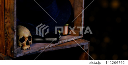 Spooky Halloween shelf with skull and witch hat, dark aesthetic and copy space of vintage aesthetic with background bokeh lights Spooky Halloween shelf with skull and witch hat, dark aesthetic and copy space of vintage aesthetic with background bokeh lights 141206762