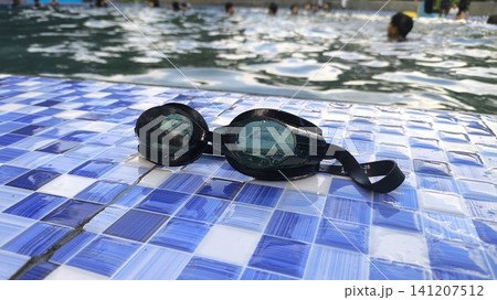 Black swim goggles rest on blue tiles Black swim goggles rest on blue tiles 141207512