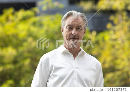 Smart and handsome senior businessman in white shirt standing in outdoor office space and park. Smart and handsome senior businessman in white shirt standing in outdoor office space and park. 141207571