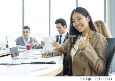 Young cheerful Asian business woman discussing project with colleagues while working together in the modern office. 141207934