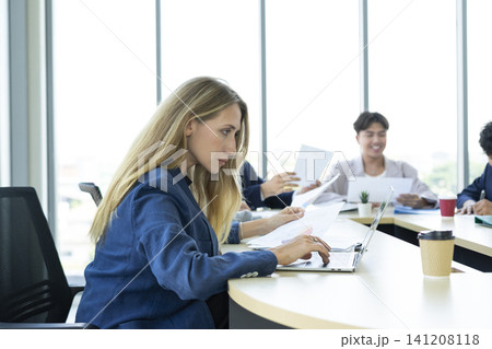 Teamwork. Side view of white woman in a office using laptop during creative meeting and drink coffee. Concept of business, office, finance, open space. 141208118