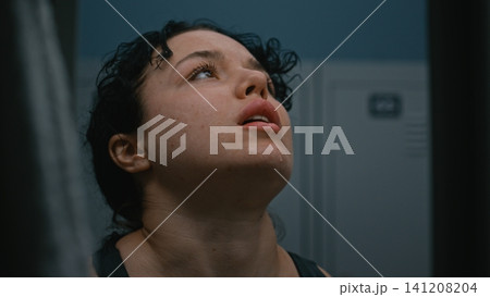 Breathless and Covered in Sweat, Young Sporty Woman in Locker Room Recovering After Training Breathless and Covered in Sweat, Young Sporty Woman in Locker Room Recovering After Training 141208204