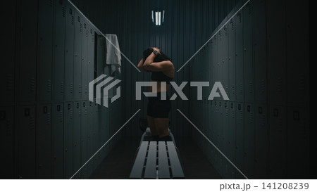 Athletic Woman Stretching Neck and Chest Muscles in Gym Locker Room Athletic Woman Stretching Neck and Chest Muscles in Gym Locker Room 141208239