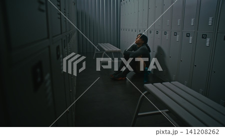 Strong Woman Going Through Moment of Despair But Not Giving Up in Empty Locker Room 141208262