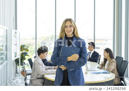 Smiling female executive looking at camera, happy businesswoman posing with office people at background. 141208298