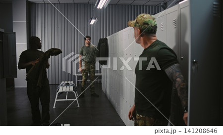 Diverse Military Officers Prepare For Training in Base Locker Room, Sharing Light Conversation Diverse Military Officers Prepare For Training in Base Locker Room, Sharing Light Conversation 141208646