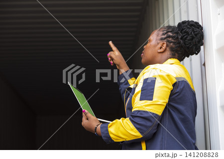 Black foreman woman worker checking stock at container yard, holding laptop computer operate loading containers. Logistics import export shipping concept. 141208828