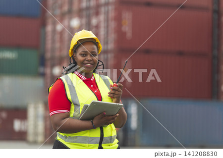 Black foreman woman worker checking stock at container yard, holding laptop computer operate loading containers. Logistics import export shipping concept. 141208830