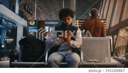 Young Male Passenger Scanning Digital Ticket and Walking to Boarding Gate Young Male Passenger Scanning Digital Ticket and Walking to Boarding Gate 141208867