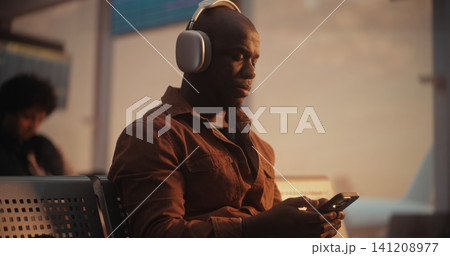 Focused Male Traveler Messaging on Phone at Airport Terminal Focused Male Traveler Messaging on Phone at Airport Terminal 141208977