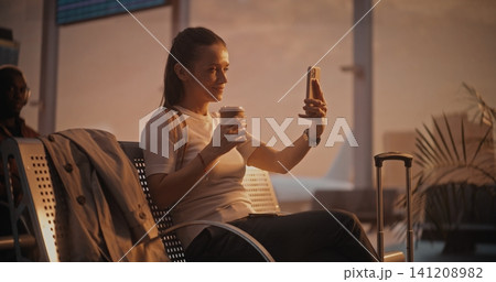 Young Woman Having Video Call with Friend at Airport Terminal 141208982