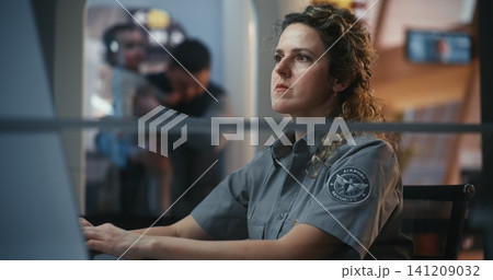 Female Airport Security Officer Monitors Baggage Conveyor System in Terminal Female Airport Security Officer Monitors Baggage Conveyor System in Terminal 141209032