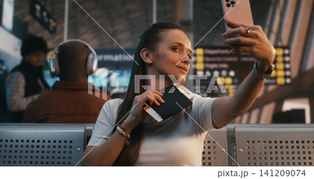 Young Female Traveler Taking Selfie with Boarding Pass at Airport Gate Young Female Traveler Taking Selfie with Boarding Pass at Airport Gate 141209074