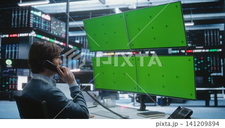 Professional Stock Broker Speaks on Desk Phone Multi Monitor Trading Workstation in Stock Exchange. 141209894