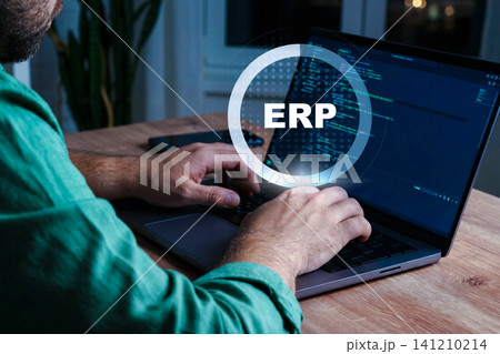 Person using laptop to work on ERP software at night in home office setting 141210214