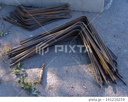 Bundles of rusty-brown, L shaped steel rebar are neatly stacked on concrete pad. Prevent bars are an essential construction material, ready for use in reinforcing structures at the construction site. 141210259