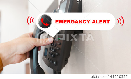Person using emergency phone in a building to report a situation during the day Person using emergency phone in a building to report a situation during the day 141210332