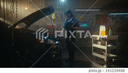 Female Auto Mechanic Connects Laptop to Car Engine For Advanced Computer Diagnostics Female Auto Mechanic Connects Laptop to Car Engine For Advanced Computer Diagnostics 141210486