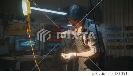 Female Auto Mechanic Checking Oil Level With Dipstick in Workshop Female Auto Mechanic Checking Oil Level With Dipstick in Workshop 141210533