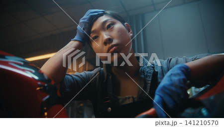 In Garage, Young Mechanic Pauses Beside Motorcycle, Thinking Intensely About How Fix Malfunction In Garage, Young Mechanic Pauses Beside Motorcycle, Thinking Intensely About How Fix Malfunction 141210570