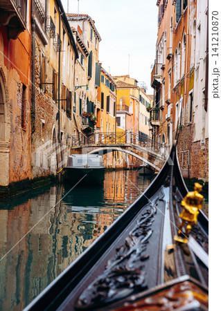 Rowing through a narrow canal in Venice with colorful buildings on both sides Rowing through a narrow canal in Venice with colorful buildings on both sides 141210870