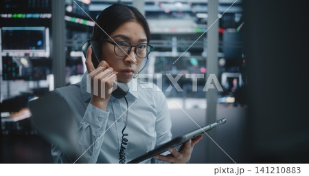 Stock Exchange Trader Compares Analytical Data on Tablet With Large Financial Charts 141210883