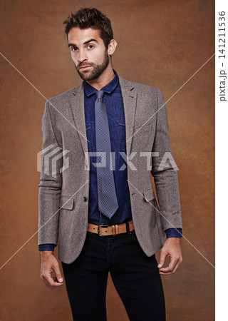 Suit, style and portrait of man in studio with confidence for trendy, classy and stylish outfit. Cool, fashion and male model with pride for elegant, fancy or luxury clothes by brown background. 141211536