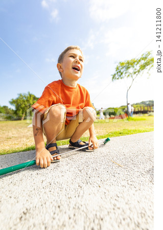Boy plays outside with a stick in a park during a sunny day Boy plays outside with a stick in a park during a sunny day 141211800
