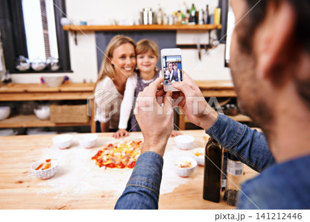 Happy family, phone and picture in kitchen for baking pizza together with parents in home. Photography, cooking and smile of mother, father and girl child on smartphone screen for bonding in house Happy family, phone and picture in kitchen for baking pizza together with parents in home. Photography, cooking and smile of mother, father and girl child on smartphone screen for bonding in house 141212446